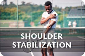 A young man stands on a tennis court holding a tennis racquet in one hand. His other hand is holding his shoulder and grimacing in pain. Title reads: Shoudler Stabilization